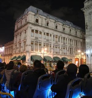 eine Gruppe von Menschen, die auf Stühlen vor einem Gebäude sitzen