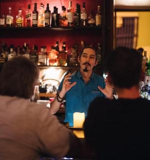 一名男子站在酒吧里与两个人交谈