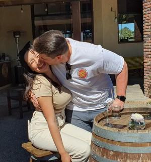 un home i una dona besant-se davant d'un barril