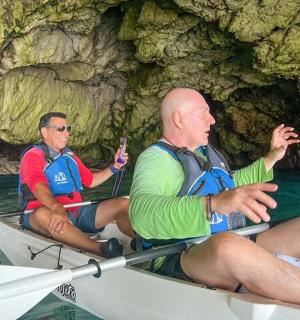 two men in a kayak in front of a cave