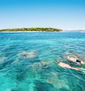 two people swimming in the ocean with an island in the background