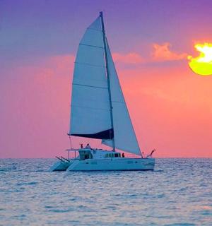 a sail boat in the ocean with a sunset