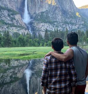a man and a boy standing in front of a waterfall