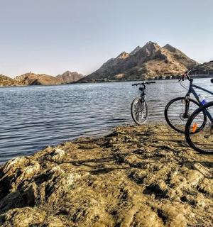 two bikes parked on the shore of a body of water