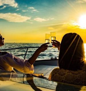 two women sitting on a boat taking a picture of the sunset