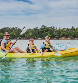 a man and two children in a yellow kayak in the water
