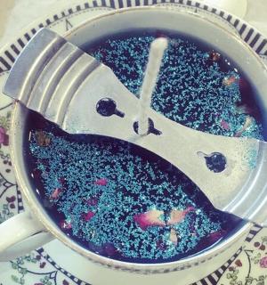 一个装满蓝莓的杯子和一把叉子放在盘子上