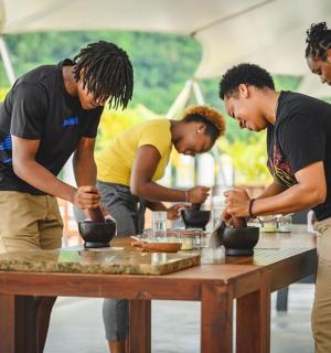 a group of people standing around a table making pottery