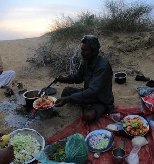 skupina lidí sedících na pláži a jedících jídlo