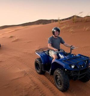 two men riding on atvs in the desert