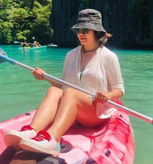 a woman sitting in a pink kayak in the water