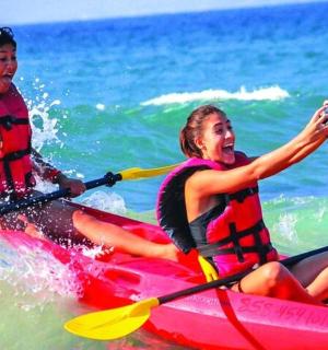 Dvě ženy jedoucí na červeném kajaku v oceánu