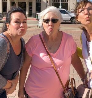 three women standing next to each other on a street
