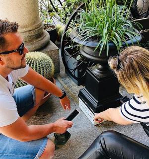 a man and a woman sitting on a bench looking at a cell phone