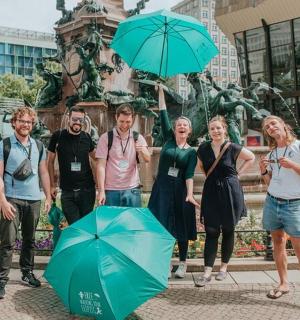 一群人站在喷泉前,打着伞