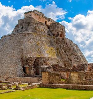 an old pyramid building with a green field in front