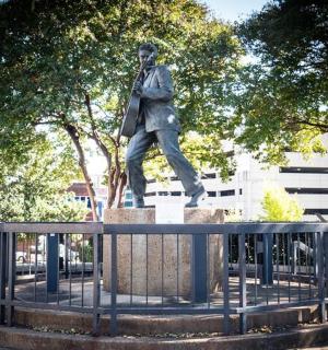 a woman standing next to a statue of a man