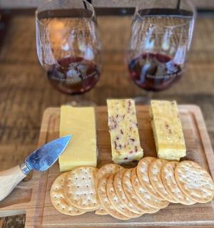 une planche à découper avec du fromage et deux verres de vin