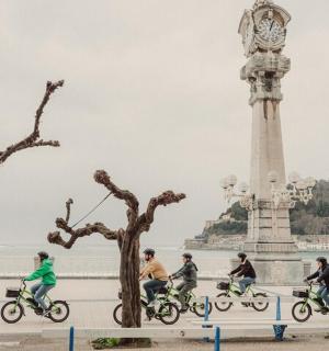 un grup de persones anant en bicicleta davant d'una torre del rellotge