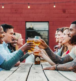 skupina lidí pijících pivo u dřevěného stolu