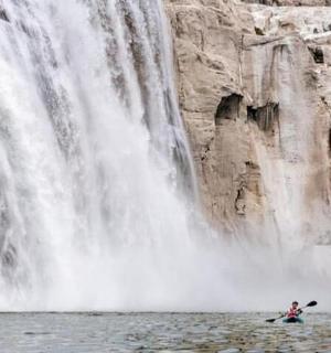 cilvēks kajakā ūdenskrituma priekšā