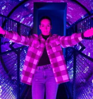 a woman standing in a purple room with her arms out