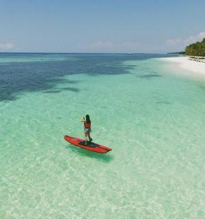 una persona in piedi su una tavola da surf rossa nell'oceano