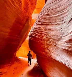 a man walking through a slot canyon