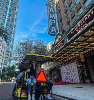 a man and woman riding a toy car on a street