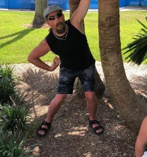a man standing next to a tree with his arm in the air