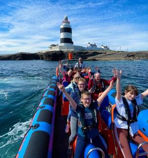 a group of people on a boat in the water with a lighthouse