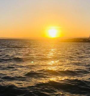 a sunset over a body of water with a lighthouse