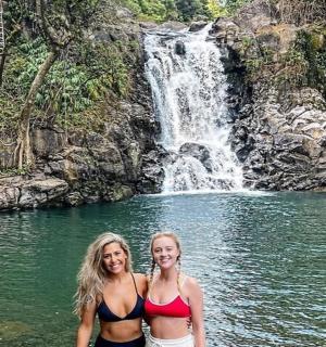 两名女子站在瀑布前的水中