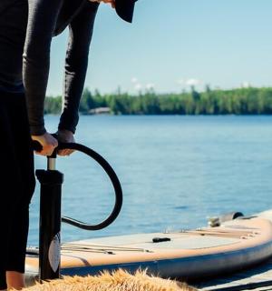 osoba držící deštník vedle paddleboardu