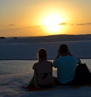 一对夫妇坐在沙滩上看日落