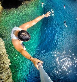 žena sahající z útesu do vody