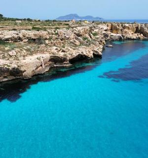 an aerial view of a rocky shoreline with blue water