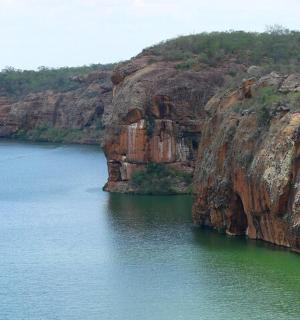 a boat in a body of water next to a cliff