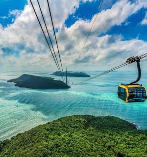 a gondola flying over the ocean near a mountain