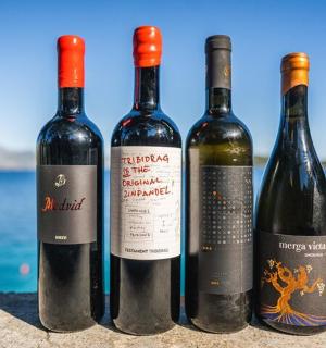 μια ομάδα τεσσάρων μπουκαλιών κρασιού που κάθονται σε έναν τοίχο