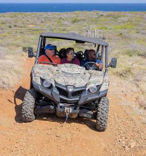 一群人坐在吉普车上，行驶在土路上