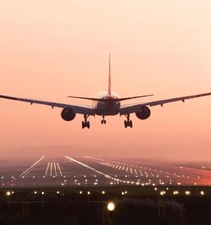 an airplane taking off from an airport runway at sunset