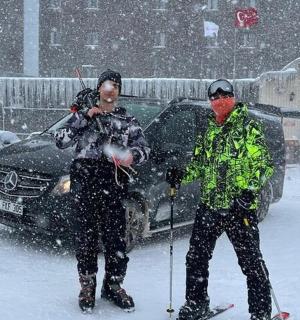 dva lidé na lyžích ve sněhu před autem