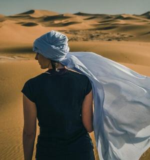 a woman walking in the desert with a veil