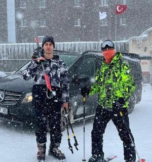 两个人在一辆汽车前的雪地里滑雪