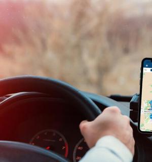 a person driving a car while holding a cell phone