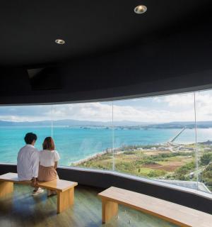 a couple sitting on a bench in front of a large window