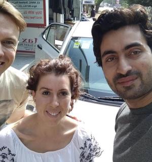 两名男子和一名女子站在一辆汽车旁边