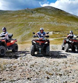 tři lidé jedoucí na čtyřkolkách na skalnatém svahu