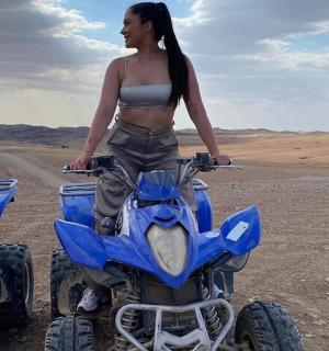 Žena sedí na čtyřkolce v poušti